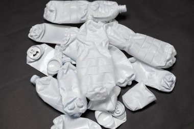 Buruşturulmuş plastik şişeler siyah bir arka plan üzerinde yatıyor. Çürümeyen atıklar ve plastik geri dönüşümü ile çevre kirliliği kavramı.
