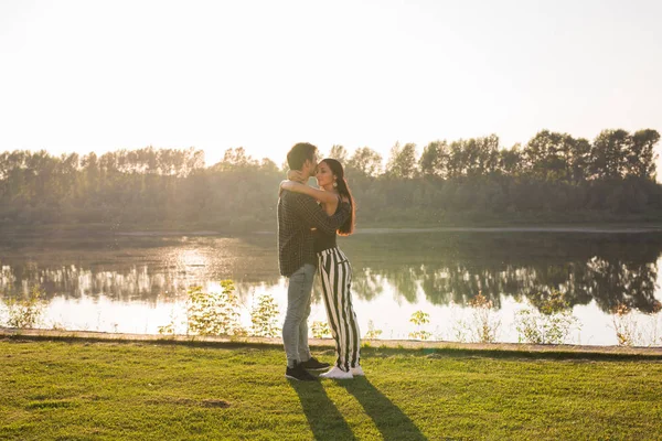 Les gens, l'amour et la nature concept - Jeune belle femme et bel homme embrassant l'autre sur fond d'eau — Photo