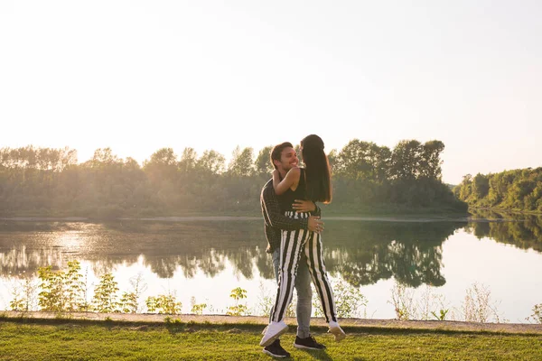 Романтика, люди и летняя концепция - мужчина поднял женщину на руках у озера на закате — стоковое фото