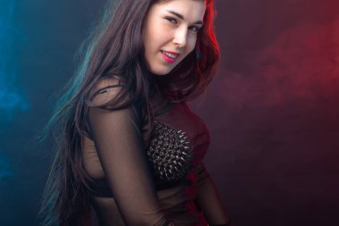 Karanlık bir arka planda poz kışkırtıcı bir elbise içinde çekici genç güzel esmer kadın. Baştan çıkarma ve cinsel çekiciliği kavramı.