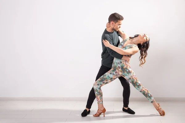 Dança social, bachata, salsa, kizomba, zouk, conceito de tango - Homem abraça mulher enquanto dança sobre fundo branco com espaço de cópia — Fotografia de Stock