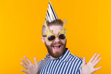 Sarı bir arka plan üzerinde bir şapka ve gözlük deli neşeli neşeli genç adam. Başarılı bir parti ve tatil kavramı.