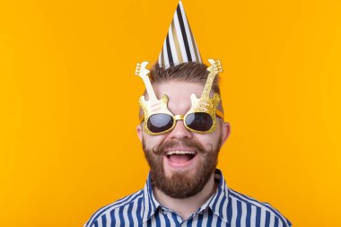 Bir kağıt kap ve gözlük joyful genç hipster erkek kopya alanı ile sarı bir arka plan üzerinde mutlu gülüyor. Bir mega parti ve tatil kavramı.