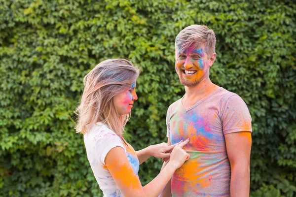 Amistad, festival de holi - mujer joven jugar con sucia camiseta de hombre joven en el festival de holi —  Fotos de Stock