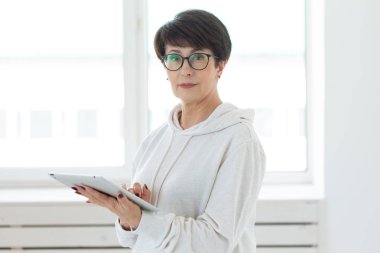 Teknolojiler ve modern insanlar kavramı-güzel kadın 50 kısa saçlı ışık odasında tablet tutarak eski yıl