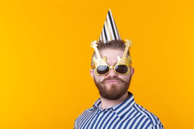 Sakal ile çılgın genç pozitif hipster adam kopya alanı ile sarı bir arka planda mutlu gülüyor. Tatil ve satış konsepti