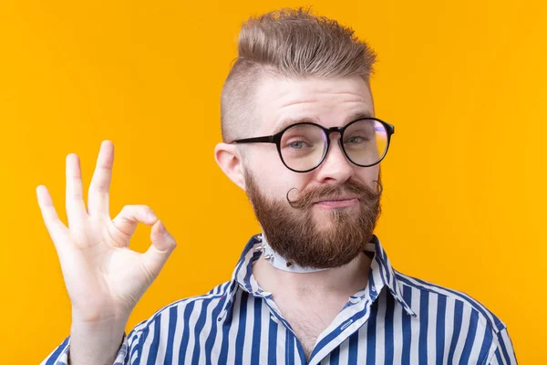 Positivo divertido hipster sin camisa chico con un collar rocker muestra bien en un fondo amarillo. Concepto de saludos inusuales . — Foto de Stock