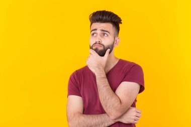 Apathetic sevimli genç Brunet adam hipster kopya alanı ile sarı bir arka plan üzerinde poz ve bir şey hakkında düşünme. Yerine getirilmemiş rüyalar kavramı.