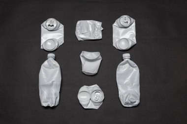 Parçalanmış plastik ve metal kutular siyah bir arka planda yatıyor. Çevre ve çürümeyen atık çöp kavramı.