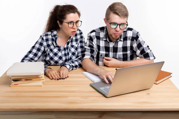 Menschen und Bildungskonzept - zwei verdutzte Studenten in karierten Hemden sitzen am Tisch — Stockfoto