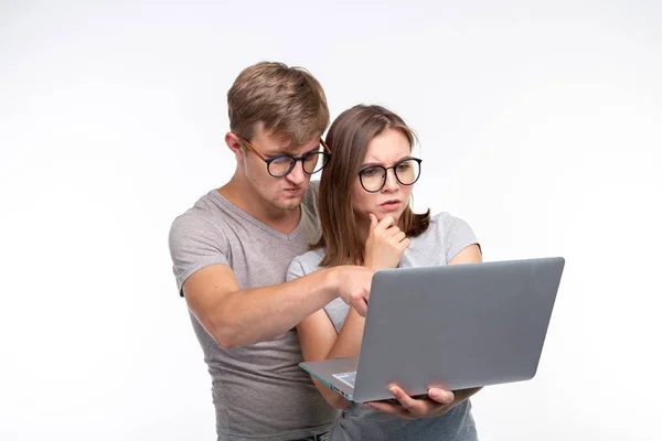 Nerds, study, people concept - a couple of students look at the netbook and look like scared on white background — Stock Photo, Image