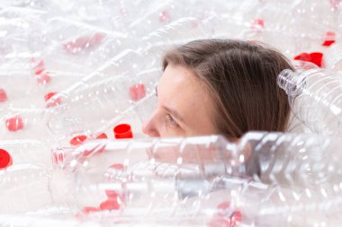 Susuz kalmış hasta kadın plastik şişeyığının içinde yatıyor. Çevre kirliliği sorunu. Doğaçöp çevre koruma konsepti durdurun