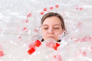 Susuz kalmış hasta kadın plastik şişeyığının içinde yatıyor. Çevre kirliliği sorunu. Doğaçöp çevre koruma konsepti durdurun