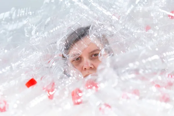 Dehydrated sjuka kvinnan ligger i en hög med plastflaskor. Miljöförorening problem. Stoppa natur sopor miljöskydd koncept — Stockfoto