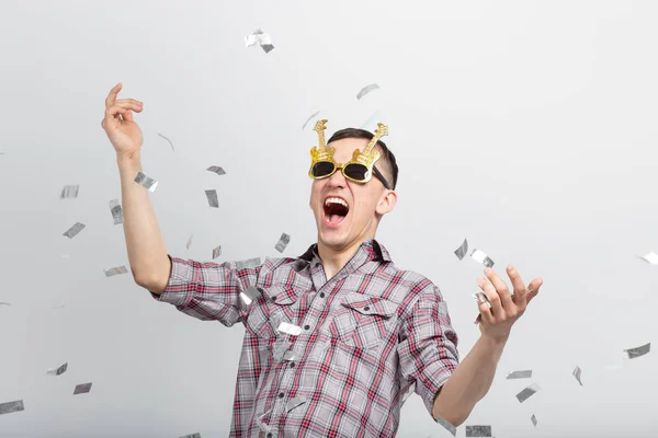 Gente, vacaciones y concepto de fiesta - chico divertido en gafas bailando en confeti sobre fondo blanco — Foto de Stock