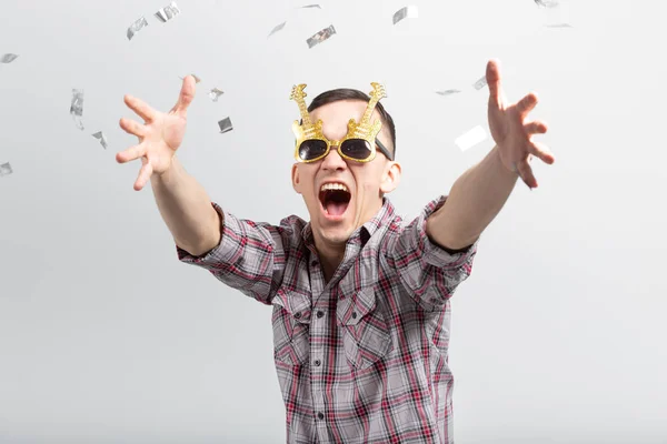 Gente, vacaciones y concepto de fiesta - chico divertido en gafas bailando en confeti sobre fondo blanco — Foto de Stock