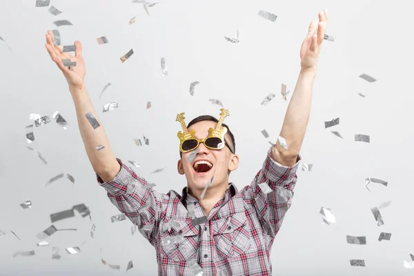 Lidé, svátky a stranou koncept - legrační chlápek v brýlích tančí v konfety na bílém pozadí — Stock fotografie