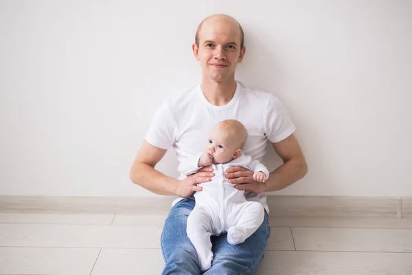 Concepto de bebé, familia y paternidad - padre calvo feliz sosteniendo a la hija del bebé de rodillas sobre un fondo blanco — Foto de Stock
