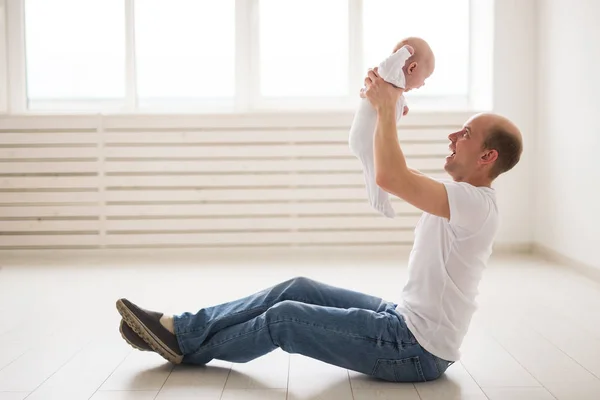 Childhood, family and fatherhood concept - proud bald father holding his newborn baby daughter in the air — Stock Photo, Image