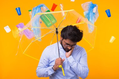 Plastik geri dönüşüm sorunu, ekoloji ve çevre felaketkavramı - Hint adam sarı arka plan üzerinde bir şemsiye altında çöpten gizleme
