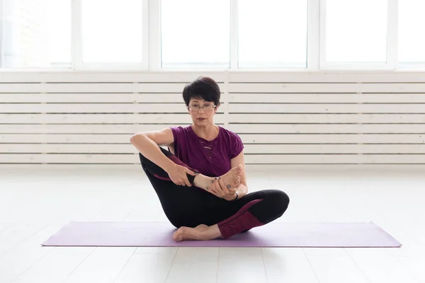 Estilo de vida saludable, personas y concepto deportivo - Mujer de mediana edad haciendo yoga — Foto de Stock