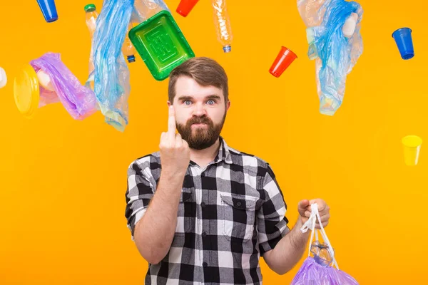 Zanieczyszczenie środowiska, problem recyklingu tworzyw sztucznych i koncepcja usuwania odpadów-zły człowiek trzyma worek na śmieci na żółtym tle. — Zdjęcie stockowe