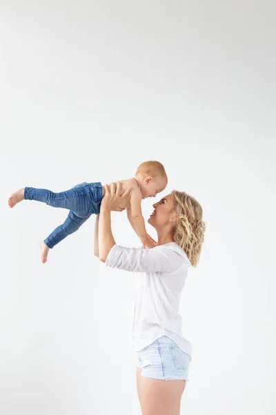 Ενιαία γονέα, μητρότητας και μωρού ιδέα-χαρούμενη μητέρα που διασκεδάζει με τη μικρή της κόρη στο στούντιο, απομονωμένη σε λευκό φόντο — Φωτογραφία Αρχείου