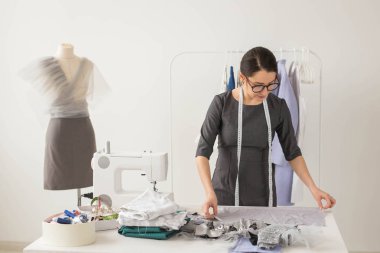 Terzi, moda tasarımcısı ve terzi kavramı - işyeri giysileri ile raf yakınındaki güzel genç stilist