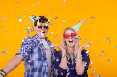 Eğlenceli, tatil ve parti konsepti - Sarı arka plan üzerinde düşen konfeti arasında çift dans