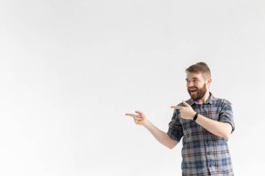 Beyaz bir arka plan üzerinde poz ve sol işaret bıyıklı Mutlu komik genç hipster adam. Sürpriz kavramı ve reklam ve bağlantılar için bir yer