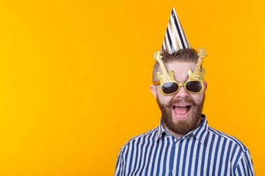 Sakal ile çılgın genç pozitif hipster adam kopya alanı ile sarı bir arka planda mutlu gülüyor. Tatil ve satış konsepti