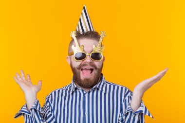 Sakallı çılgın genç pozitif hipster adam mutlu sarı bir arka plan üzerinde gülüyor. Tatil ve satış kavramı