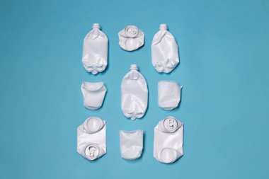 Parçalanmış plastik ve metal kutular mavi arka planda yatıyor. Çevre ve çürümeyen atık çöp kavramı.