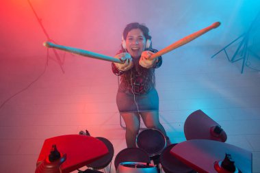 Müzik, hobi ve insan kavramı - kulaklık seksi kadın esmer stüdyoda elektronik davul kiti üzerinde çalış