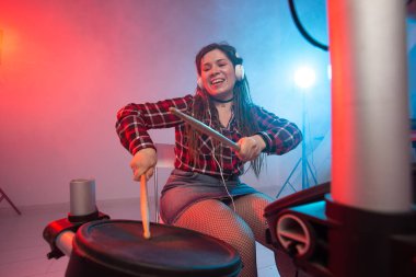 Müzik, hobi ve insan kavramı - kulaklık seksi kadın esmer stüdyoda elektronik davul kiti üzerinde çalış