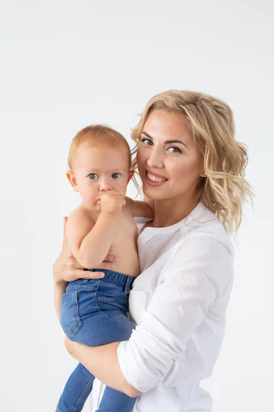 Madre soltera, maternidad y concepto de bebé - Alegre madre divirtiéndose con su hija pequeña en el estudio, aislada sobre fondo blanco — Foto de Stock