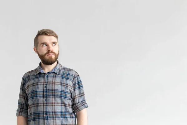 Jonge man met een snor en baard het maken van uitpuilende ogen in verrassing tegen een witte achtergrond met Kopieer ruimte. Concept van verrassing en onzekerheid. — Stockfoto