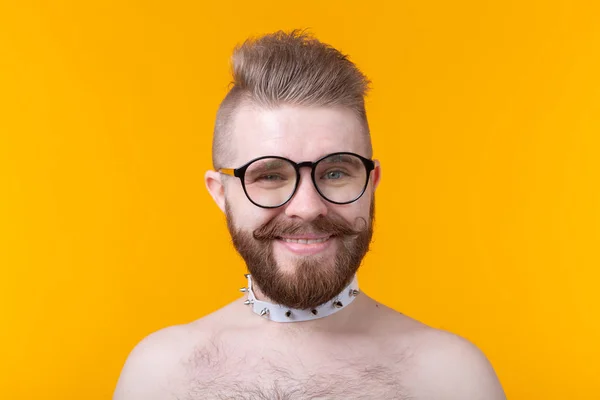 Joven hombre de moda positivo hipster con una barba bigote y collar fetiche en camisa posando sobre un fondo amarillo. Concepto de roca y subcultura . —  Fotos de Stock