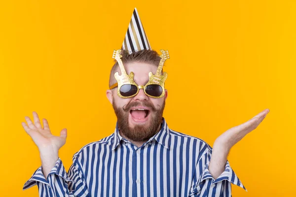 Szalony młody pozytywny facet Hipster z brodą śmieje się szczęśliwie na żółtym tle. Koncepcja święta i sprzedaży — Zdjęcie stockowe
