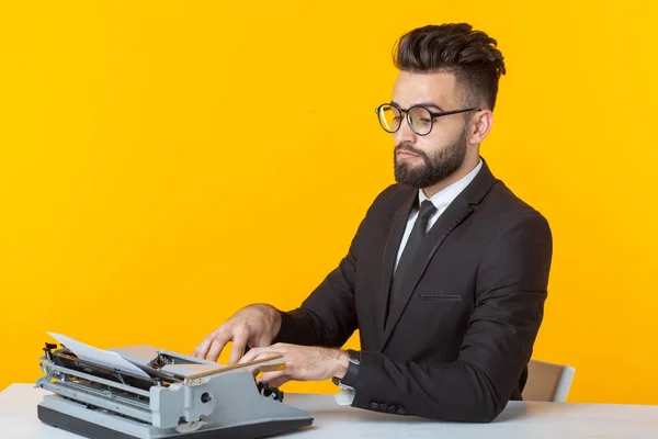 Vue latérale d'un jeune homme d'affaires charmant en tenue formelle et lunettes tapant sur une machine à écrire texte. Concept d'affaires et d'idées . — Photo