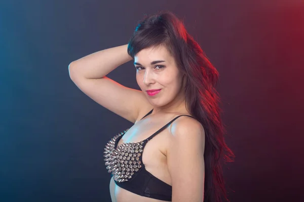 Schöne junge sexy brünette Frau posiert auf einem dunklen Hintergrund in einem genieteten Oberteil auf einem dunklen Hintergrund. das Konzept der Pflege und Attraktivität. — Stockfoto