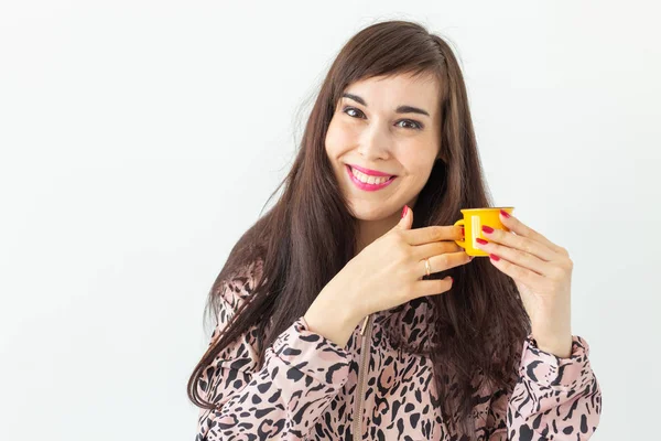 Schattige jonge vrouw met een klein speeltje Gele mok in haar handen poseren op een witte achtergrond met Kopieer ruimte. Favoriete dranken concept — Stockfoto