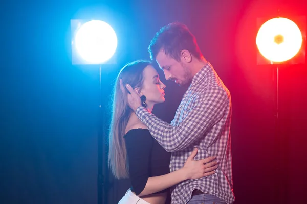 Baile social, bachata, salsa, kizomba, zouk, concepto de tango - Hombre abraza a mujer mientras baila sobre luces — Foto de Stock