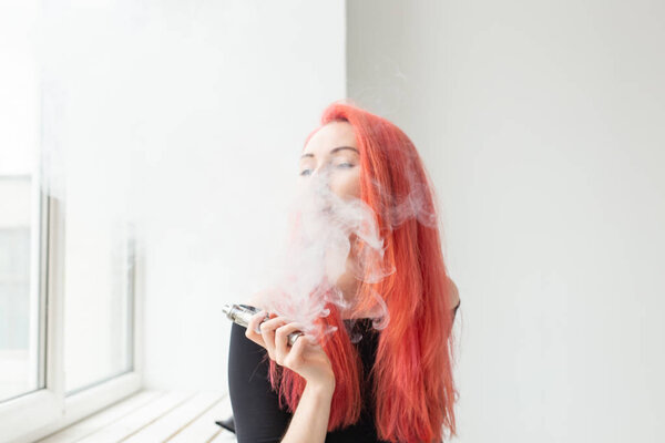 Вапе, зависимость и понятие людей - молодая женщина с раскрашенными волосами курит вапе
