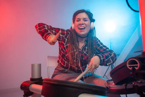 Elektronik davul seti, müzik ve hobi konsepti - genç kadın davulcu kulaklık çalıyor
