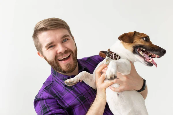 Animal, mascota y gente concepto - sonriente hombre feliz sosteniendo su pequeño gato russell terrier perro sobre fondo blanco — Foto de Stock