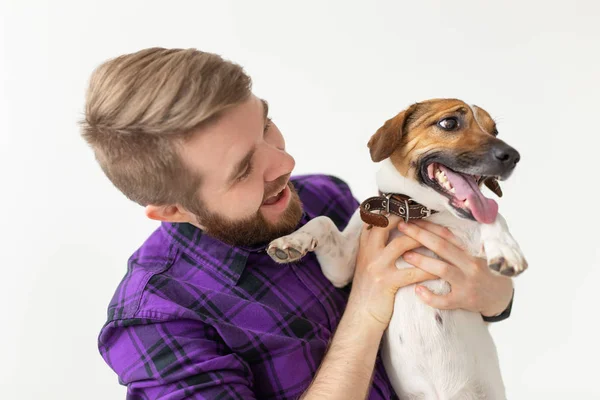 Mascotas concepto de propietario - Hombre feliz sosteniendo un perro Jack Russell Terrier sobre el fondo blanco — Foto de Stock
