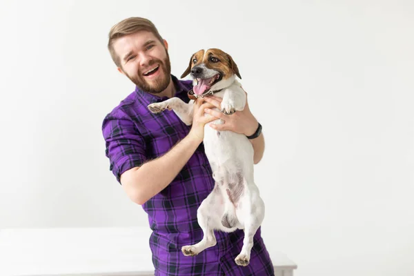 Animal, mascota y gente concepto - sonriente hombre feliz sosteniendo su pequeño gato russell terrier perro sobre fondo blanco con espacio de copia — Foto de Stock