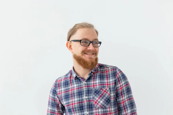 Las emociones positivas y el concepto de la gente - el joven barbudo en gafas sonríe sobre un fondo blanco — Foto de Stock