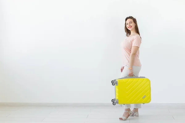 Concepto de viaje, viaje y vacaciones: mujer con su maleta amarilla sobre fondo blanco con espacio para copiar — Foto de Stock